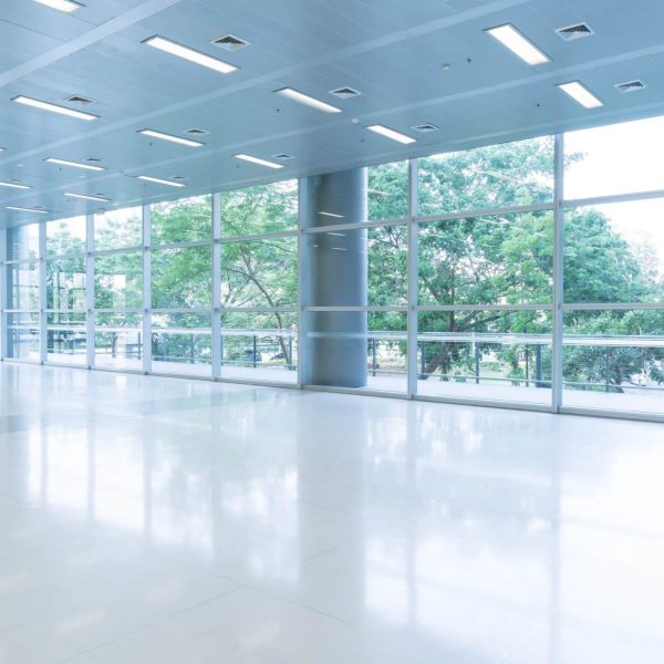 Blurred abstract background interior view looking out toward to empty office lobby and entrance doors and glass curtain wall with frame - blue white balance processing style